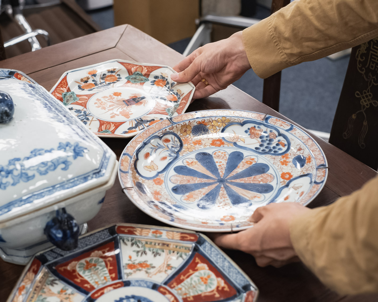 Hand arrangiert gefärbte Keramikteller mit blauen und orangefarbenen Blumen- und geometrischen Mustern auf einem Ausstellungstisch.